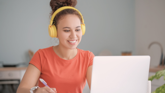 Une adolescente travaille sur son ordinateur avec un casque.