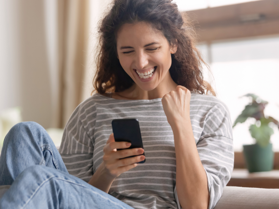 Une femme sur son téléphone portable, fait un signe de victoire.