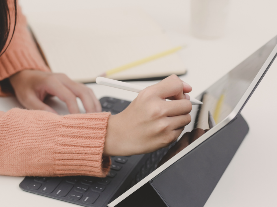 Des mains féminines écrivent sur une tablette.