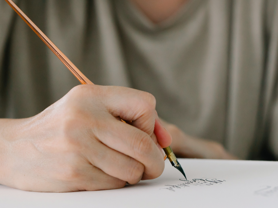 Une main masculine écrit une lettre à l'aide d'un stylo plume.