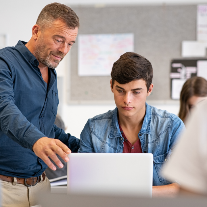 Un enseignant aide un élève à utiliser un ordinateur portable en classe