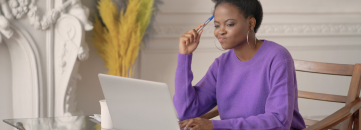 Une femme en train de travailler sur son ordinateur portable réfléchit.