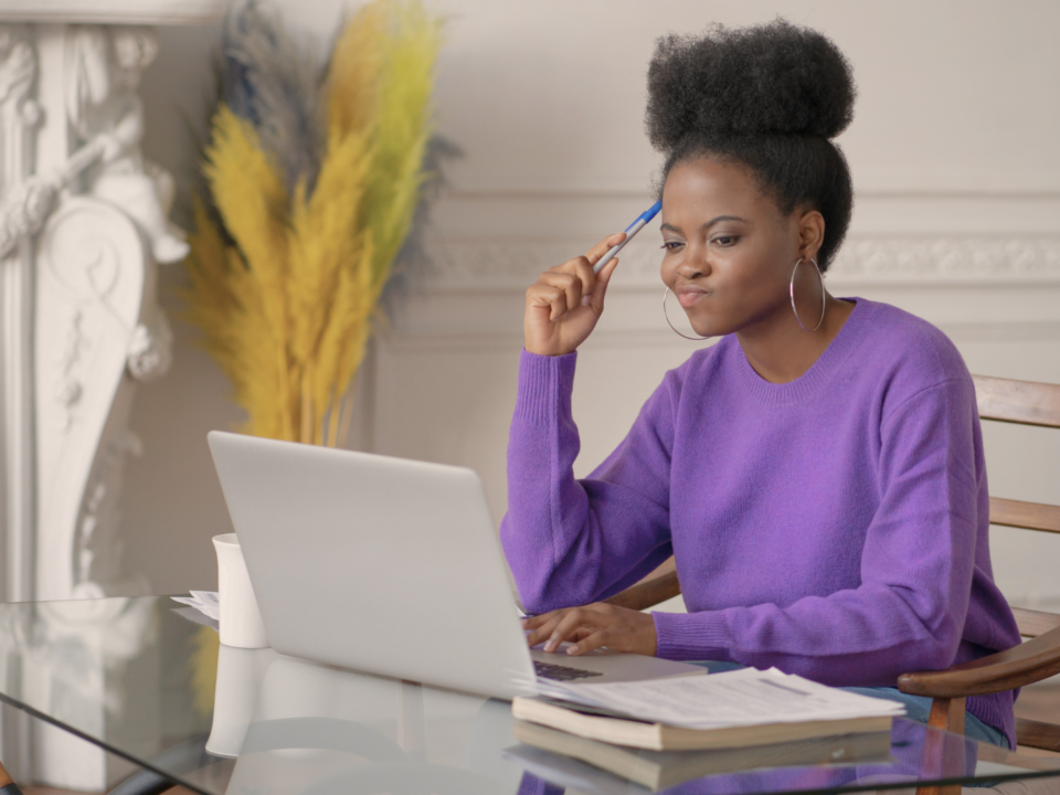 Une femme en train de travailler sur son ordinateur portable réfléchit.
