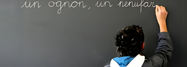 Un enfant écrit au tableau à craie.