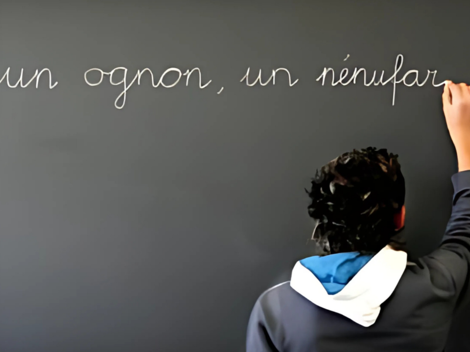 Un enfant écrit au tableau à craie.